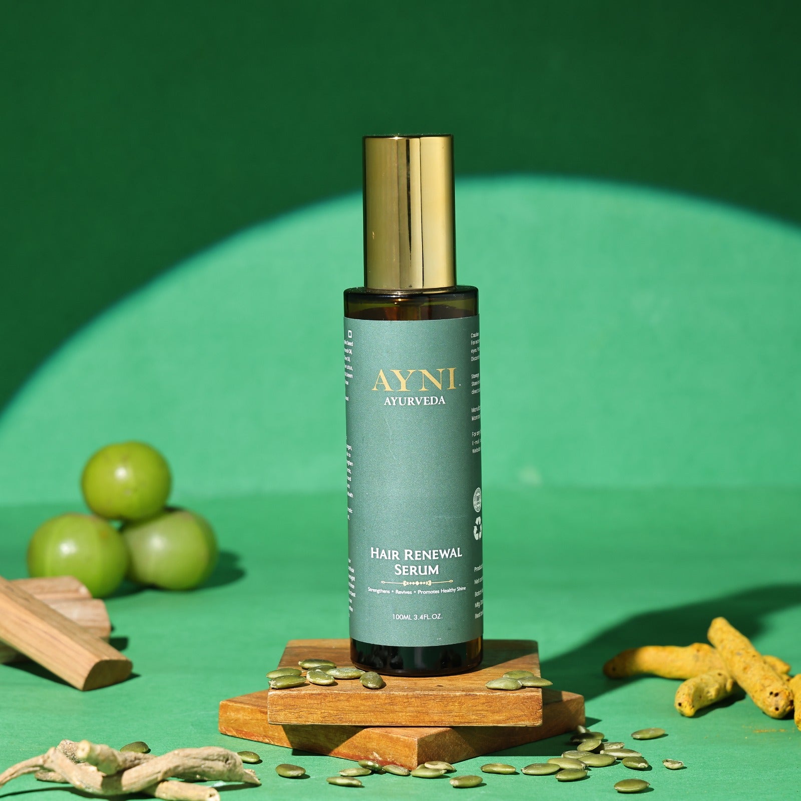 Ayni Ayurveda Hair Renewal Serum bottle on a green background with turmeric and other ingredients.