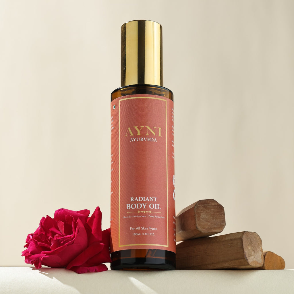 Ayni Ayurveda Radiant Body Oil bottle with a pink rose and wooden elements on a beige background