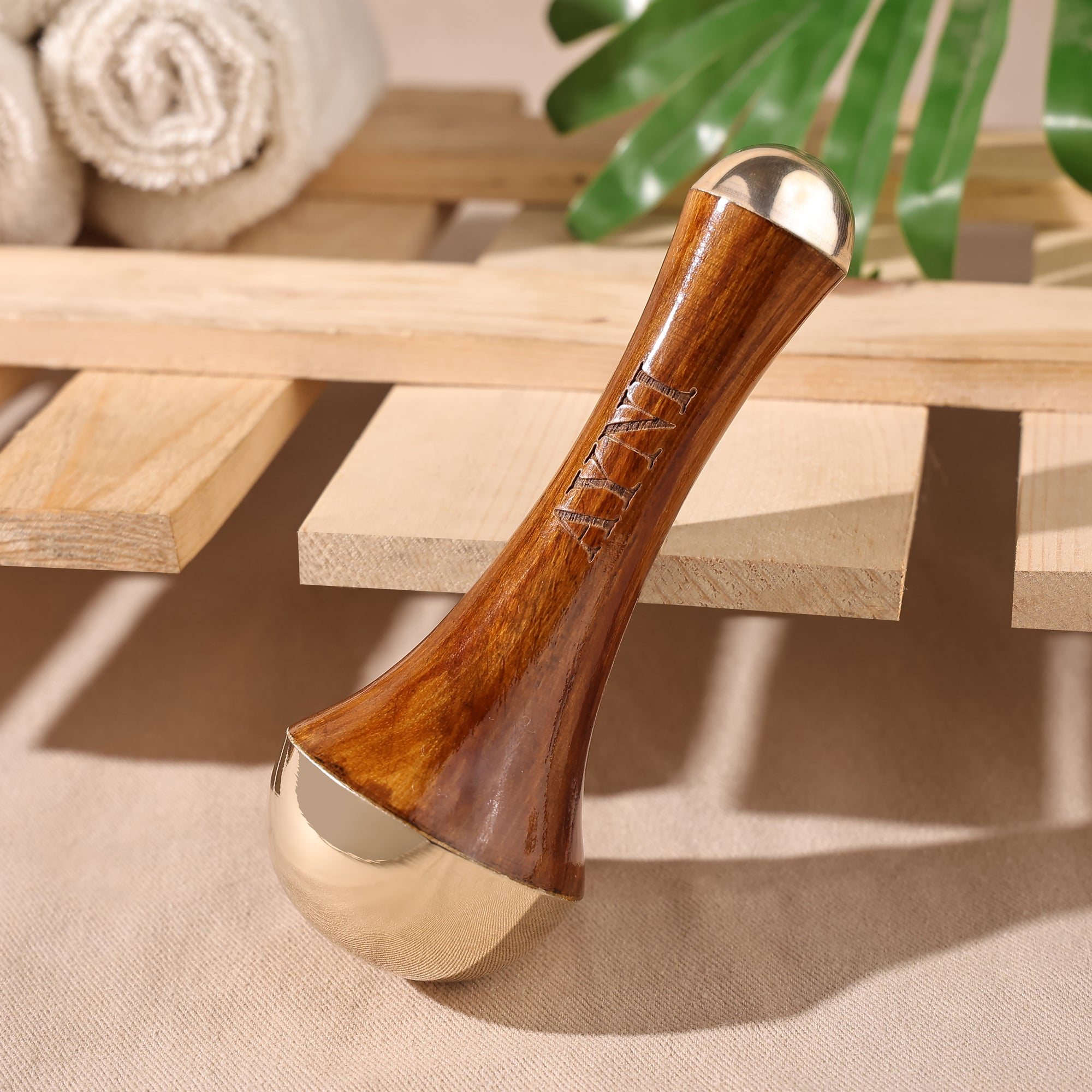 Wooden and metallic tool on a wooden surface with towels and greenery in the background