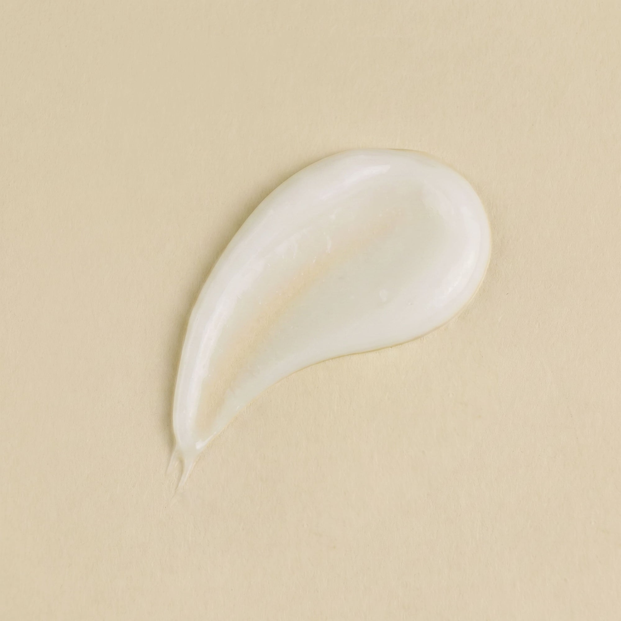 White cream droplet on a beige background